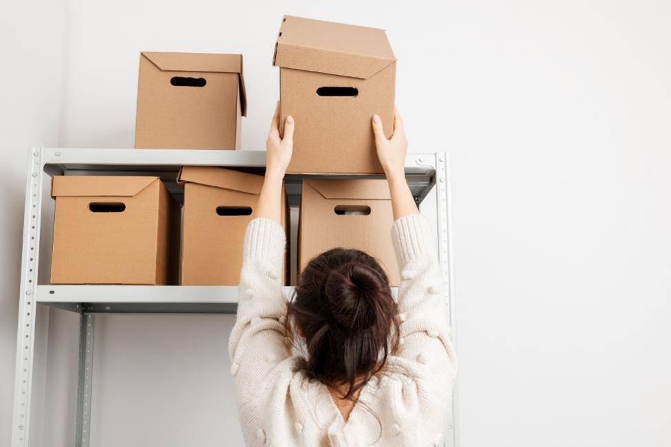 A woman putting a box on a shelf