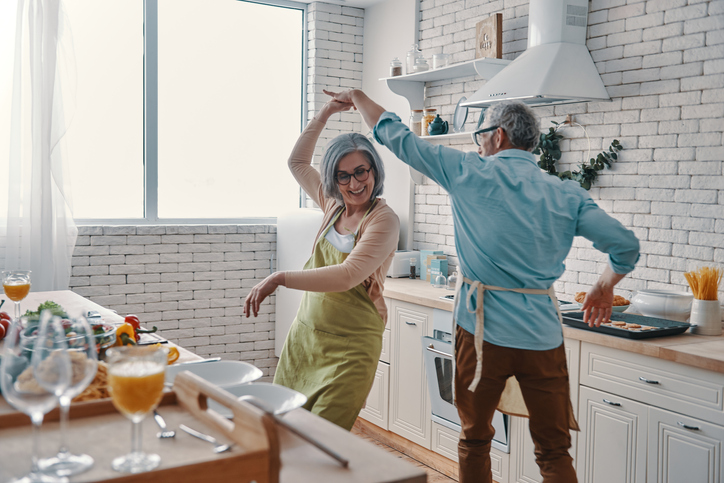 senior couple in aprons dancing and smiling