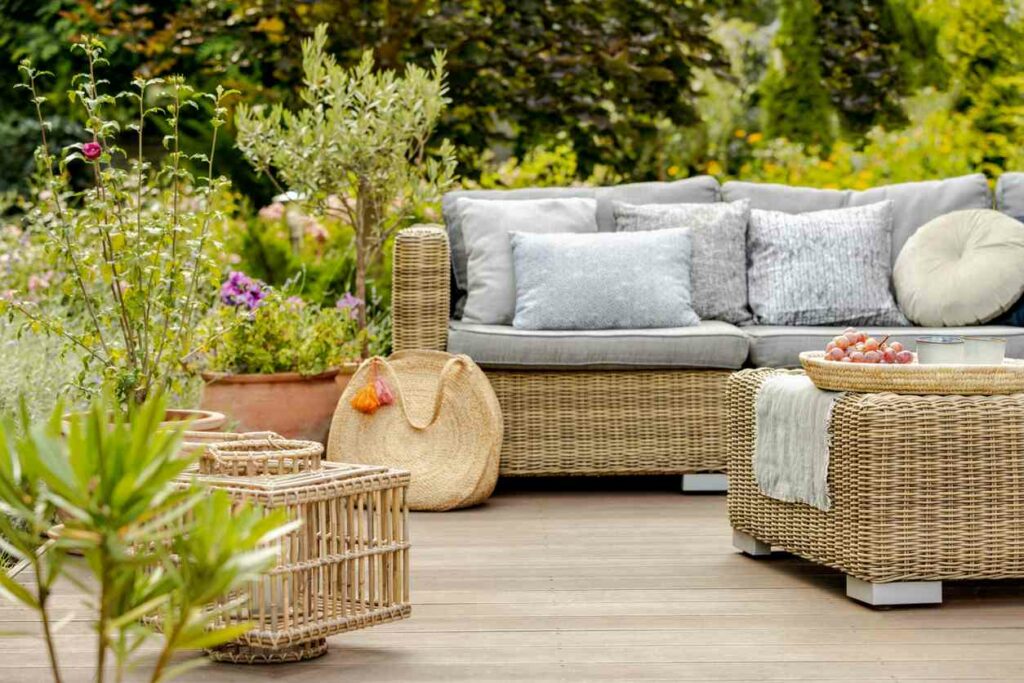 Modern wicker patio furniture surrounded by plants and foliage on a deck