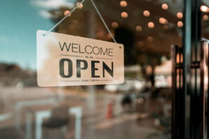 A welcome sign hangs in the window of a business, letting people know they are open