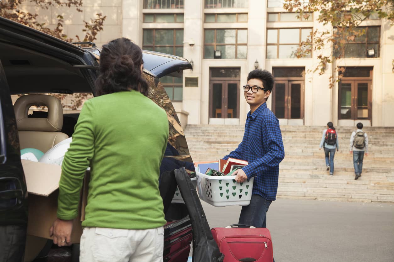 A young student and a family member load up their car as he moves out of his dorm.