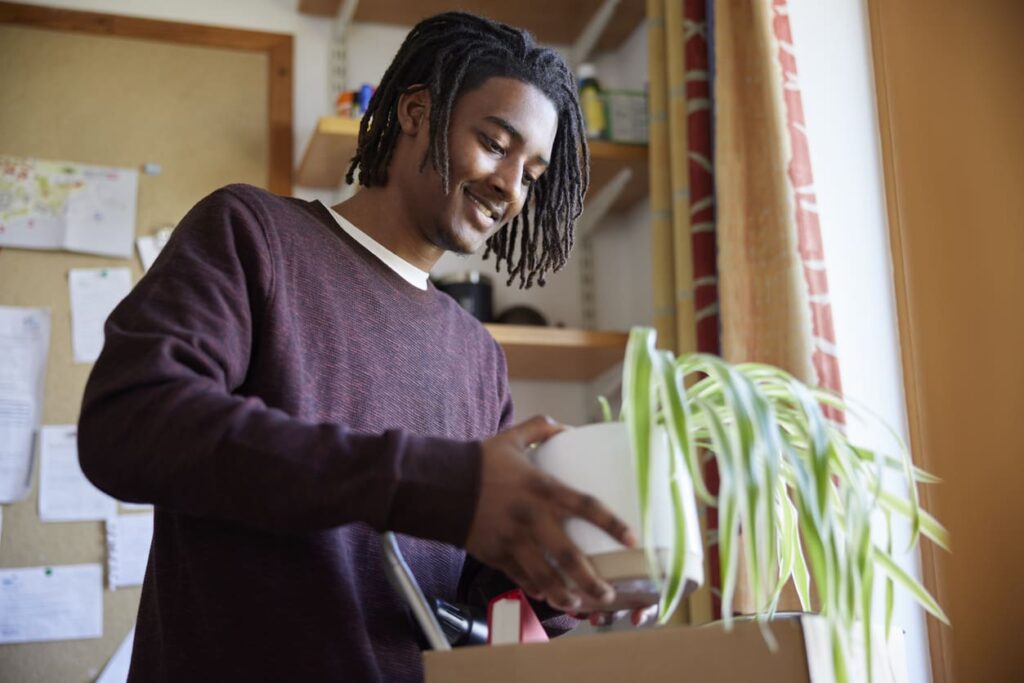 A young student loads items into a box as he moves out of his dorm.