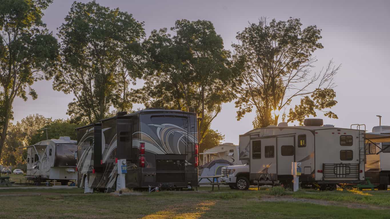 A group of RVs sit in the shade at a campground.