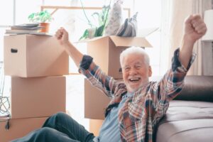 An older gentleman celebrates while packing his home during downsizing.