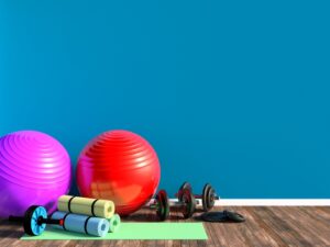 Many large inflatable fitness balls and weights sitting on the floor of an at-home gym.
