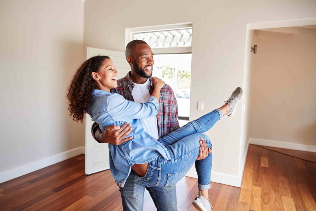 A happy newlywed couple walks into their new home together.