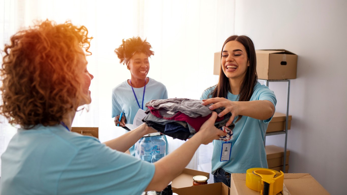 A group of volunteers at a community resource center organizes donations into cardboard boxes.