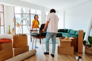 A young couple moves furniture out of their home and into temporary storage while moving.
