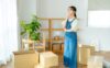 A young woman packing boxes in her living room.