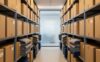 Neatly organized storage unit with uniform boxes, folded blankets, and shelving units under warm ambient lighting.