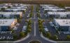Aerial view of a tidy suburban industrial district at golden hour featuring organized buildings and tree-lined roads.
