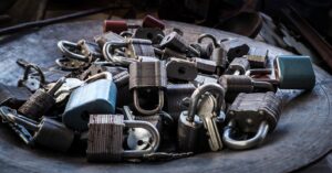 Four silver padlocks, both keyed and combination dial styles, stacked together for securing storage units.